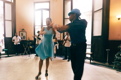 Casal dança em um salão elegante, em uma cena que remete aos musicais clássicos.