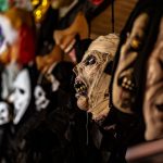 Coleção de máscaras assustadoras expostas em um ambiente escuro e cenográfico