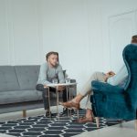 Dois homens conversam durante uma sessão de terapia em um escritório moderno.