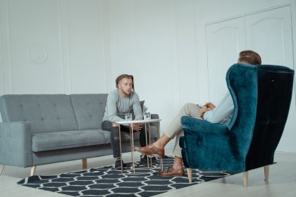 Dois homens conversam durante uma sessão de terapia em um escritório moderno.